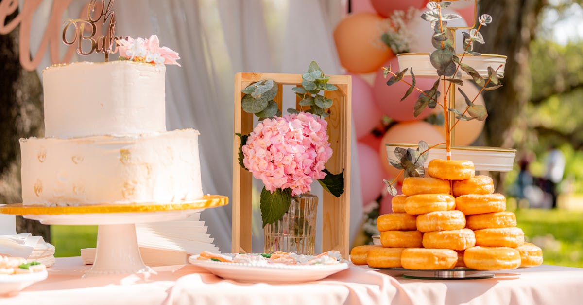 a beautifully decorated outdoor dessert table set for a baby shower featuring a cake and donuts