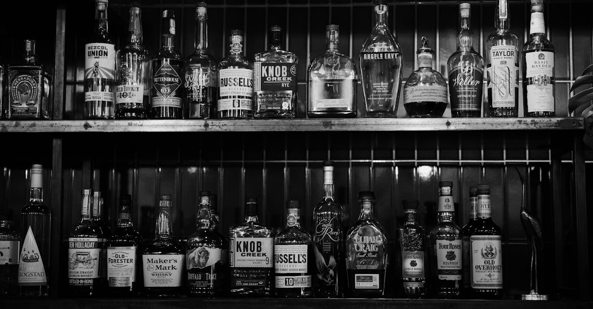 a black and white image showing various alcohol bottles on bar shelves