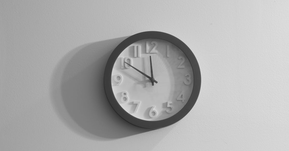 a black and white wall clock casting a shadow against a plain wall