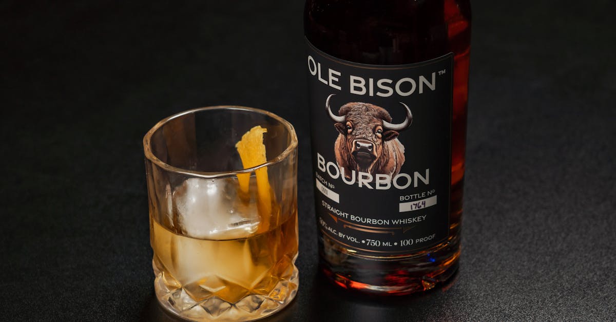 a bottle of ole bison bourbon alongside a glass of whiskey with ice and orange peel