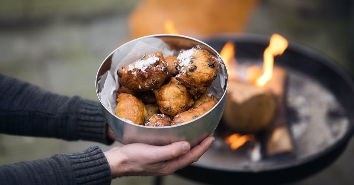 a bowl of homemade dutch oliebollen held outdoors near a cozy fire