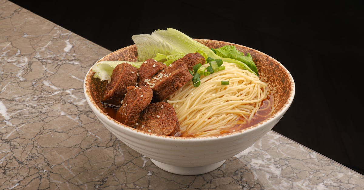 a bowl of spicy tofu noodles and fresh lettuce served on a marble countertop
