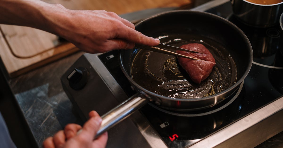 a chef sears a steak in a skillet on an induction cooktop in a professional kitchen 2