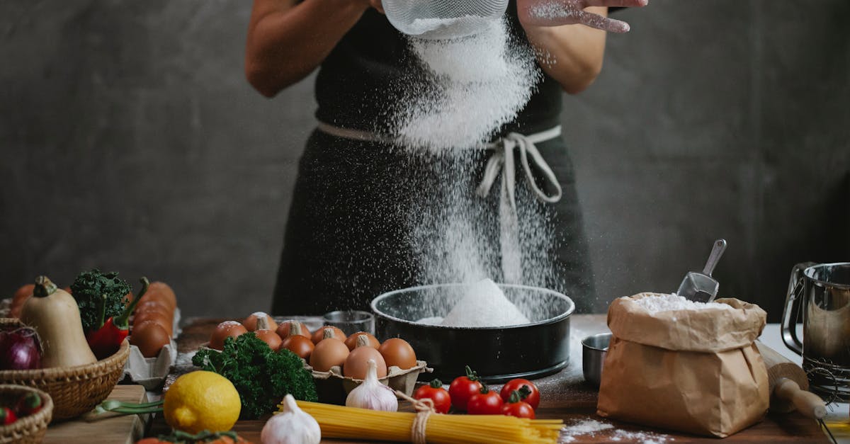 a chef sifts flour onto a cutting board surrounded by fresh ingredients for homemade pasta