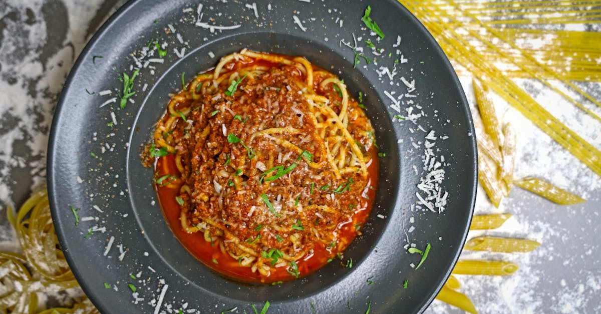 a close up of a flavorful spaghetti bolognese topped with parmesan cheese on a dark plate
