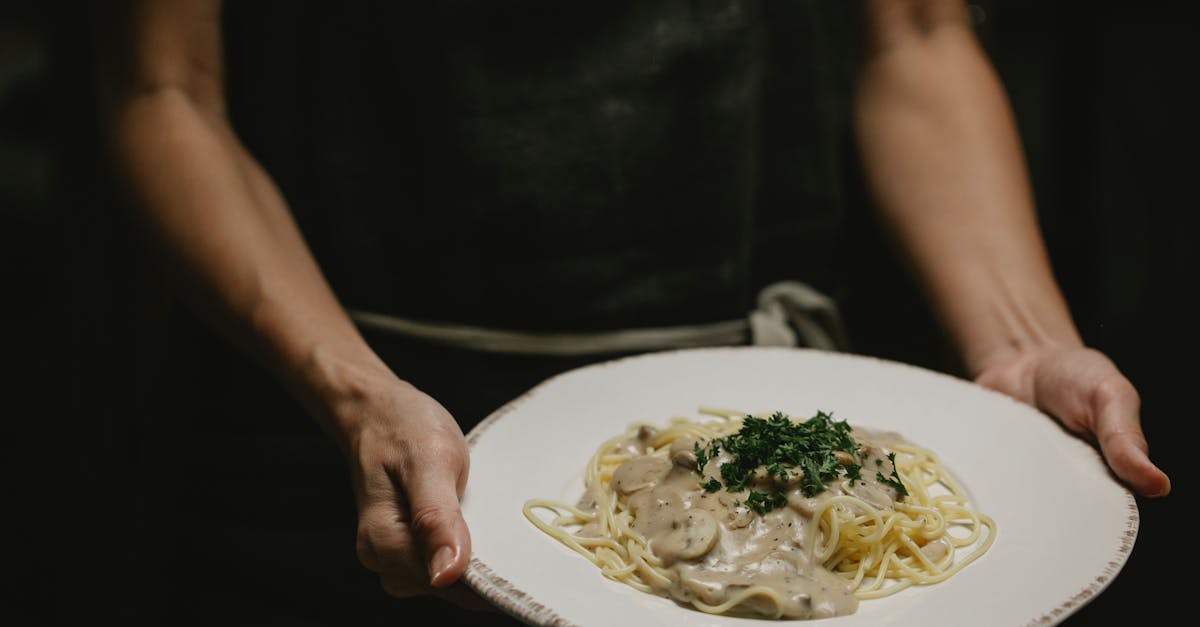 a close up of creamy mushroom pasta held by a chef perfect for gourmet cuisine enthusiasts