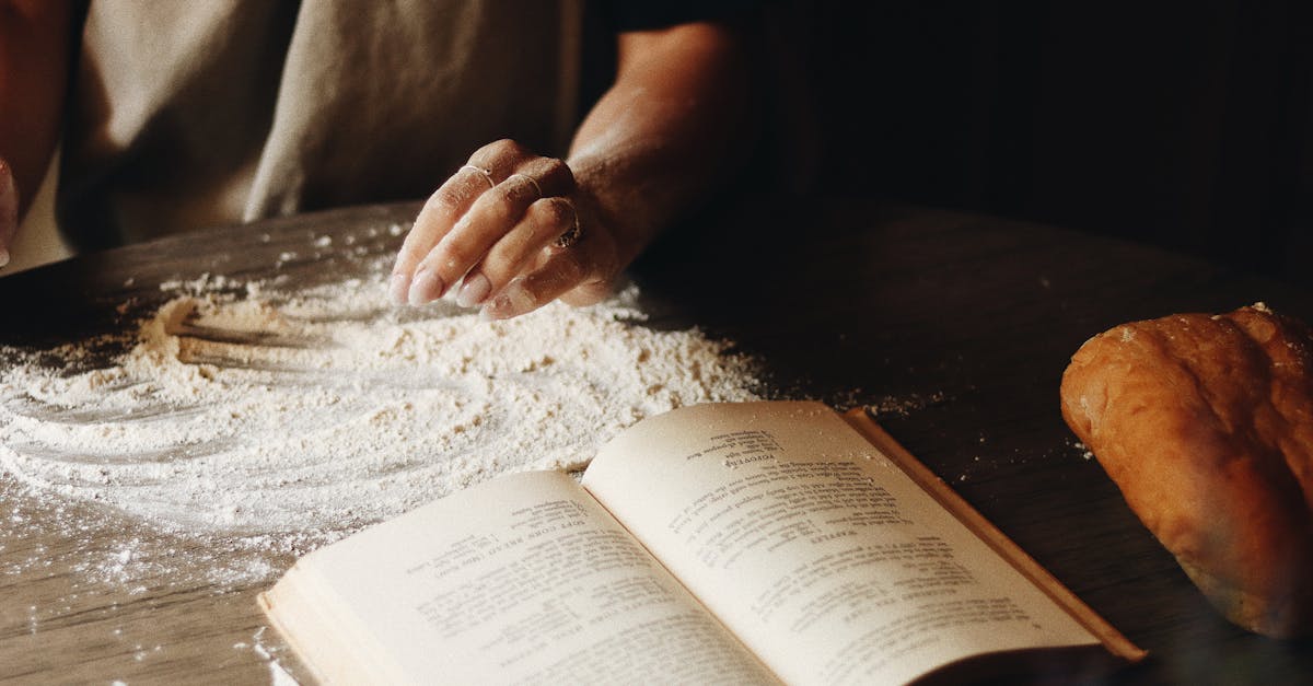a close up of hands shaping dough beside an open recipe book capturing the art of home baking