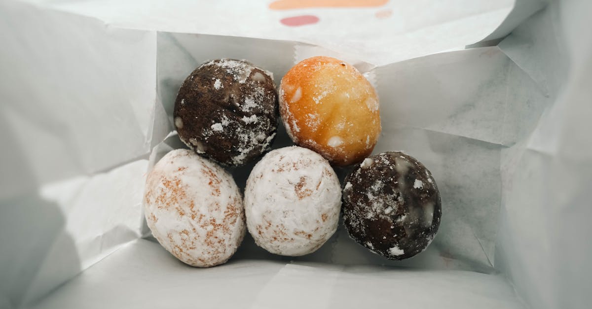 a close up view of assorted donut holes in a paper bag perfect for food lovers 2