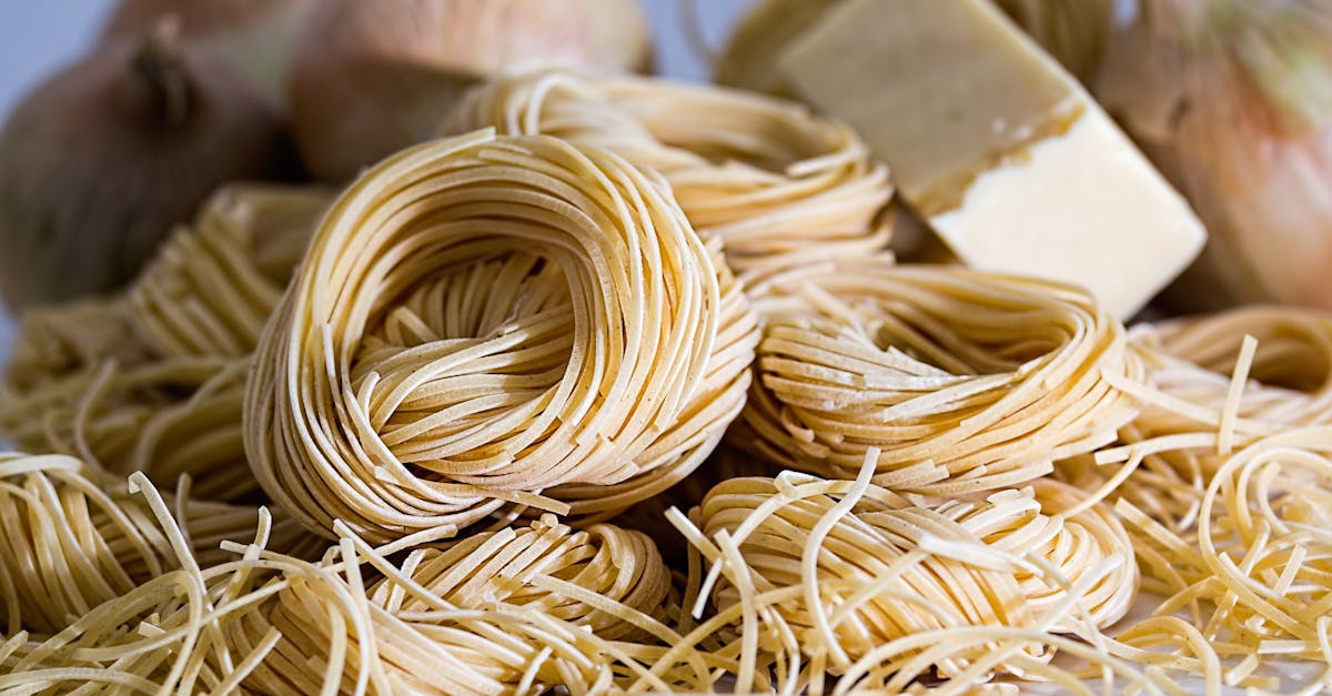 a close up view of uncooked capellini pasta nests surrounded by onions and cheese 1