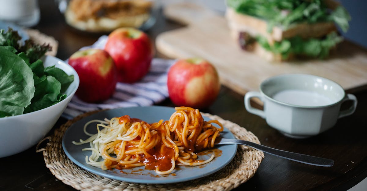 a cozy meal setup with spaghetti fresh apples greens and bread on a wooden table 3