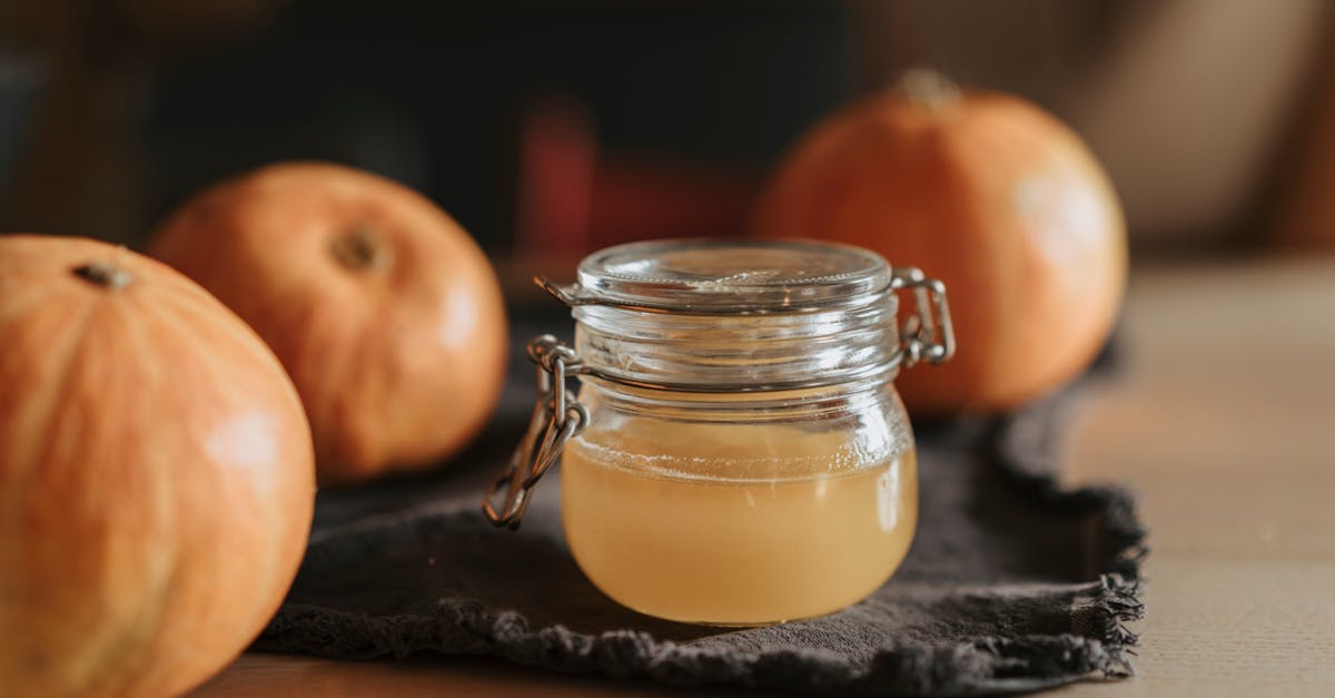 a cozy still life with homemade apple cider in a glass jar surrounded by pumpkins on a wooden table 1
