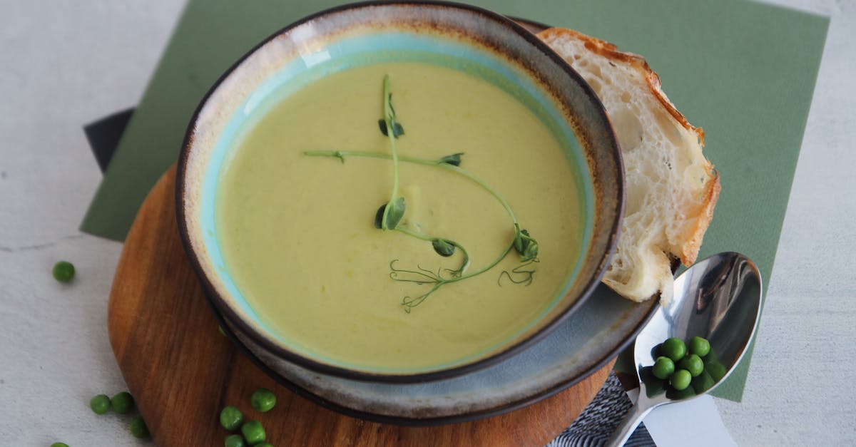 a creamy green pea soup served in a bowl with fresh bread on a wooden board 1
