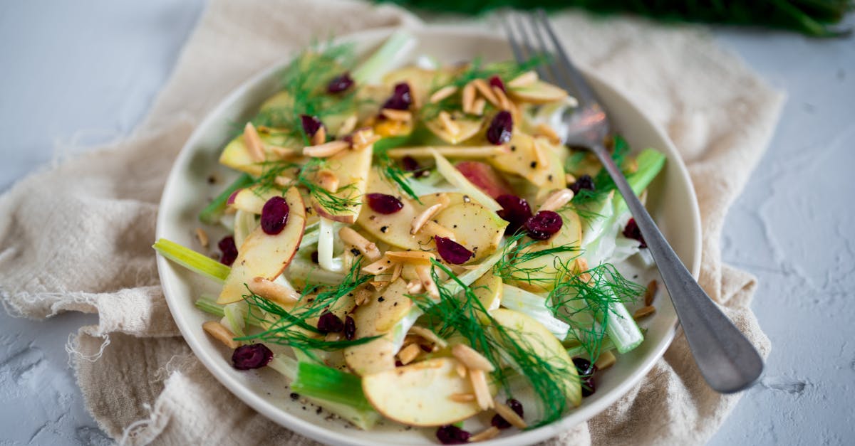 a delicious apple and fennel salad garnished with almonds and cranberries on a ceramic plate 2