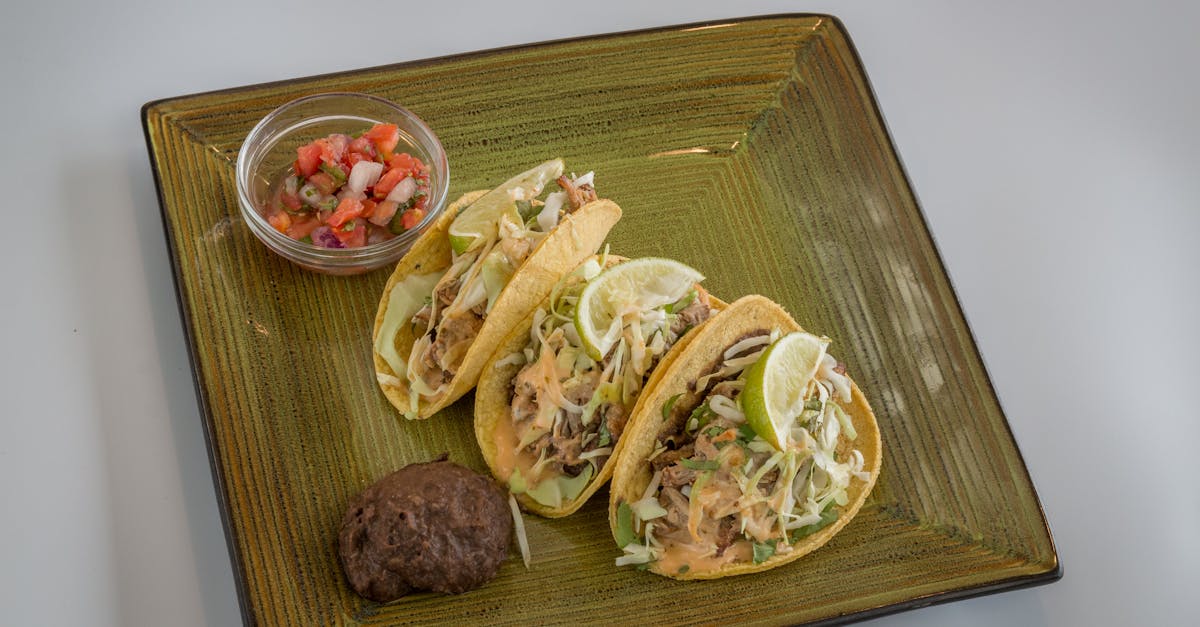 a delicious serving of tacos with lemon slices salsa and black beans on a textured plate