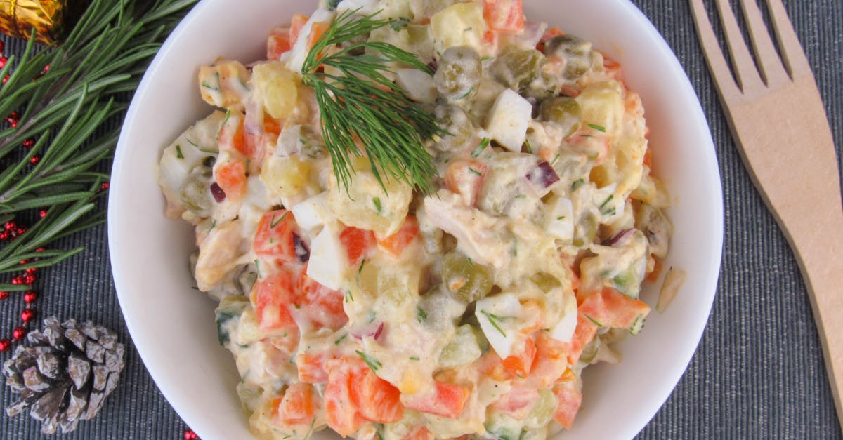 a delicious vegetable salad with dill mayonnaise and carrots served in a white bowl