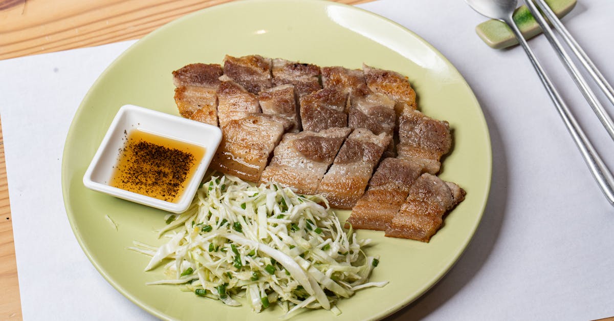 a deliciously plated grilled pork dish served with fresh cabbage slaw and a flavorful dipping sauce