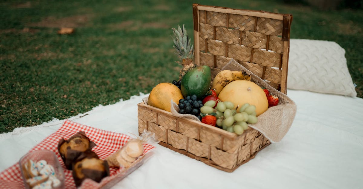 a delightful picnic scene showcasing a fruit basket and pastries on a white blanket outdoors