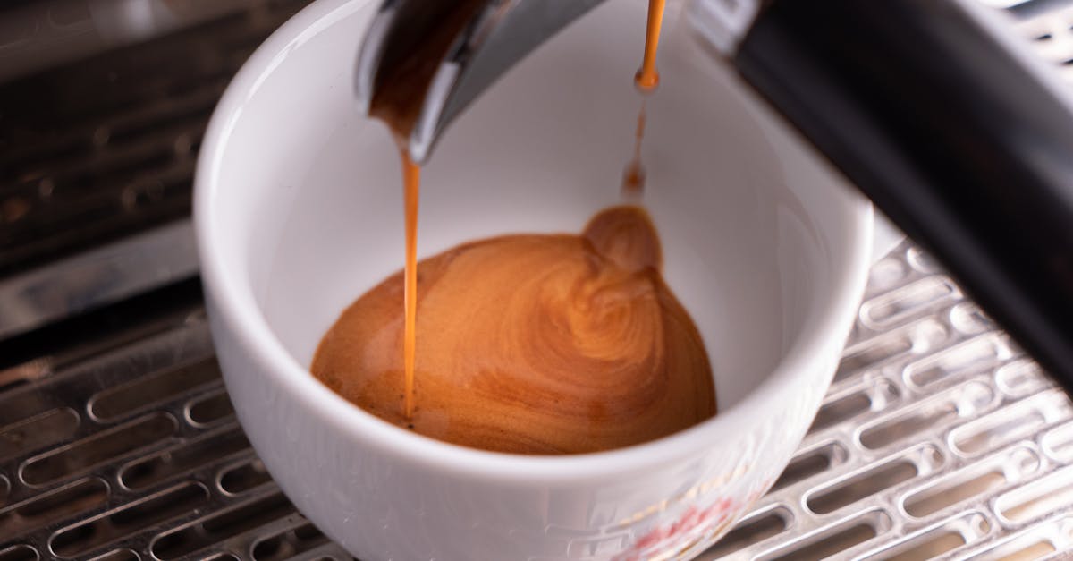a detailed view of espresso coffee being poured into a white cup from a machine highlighting the ri