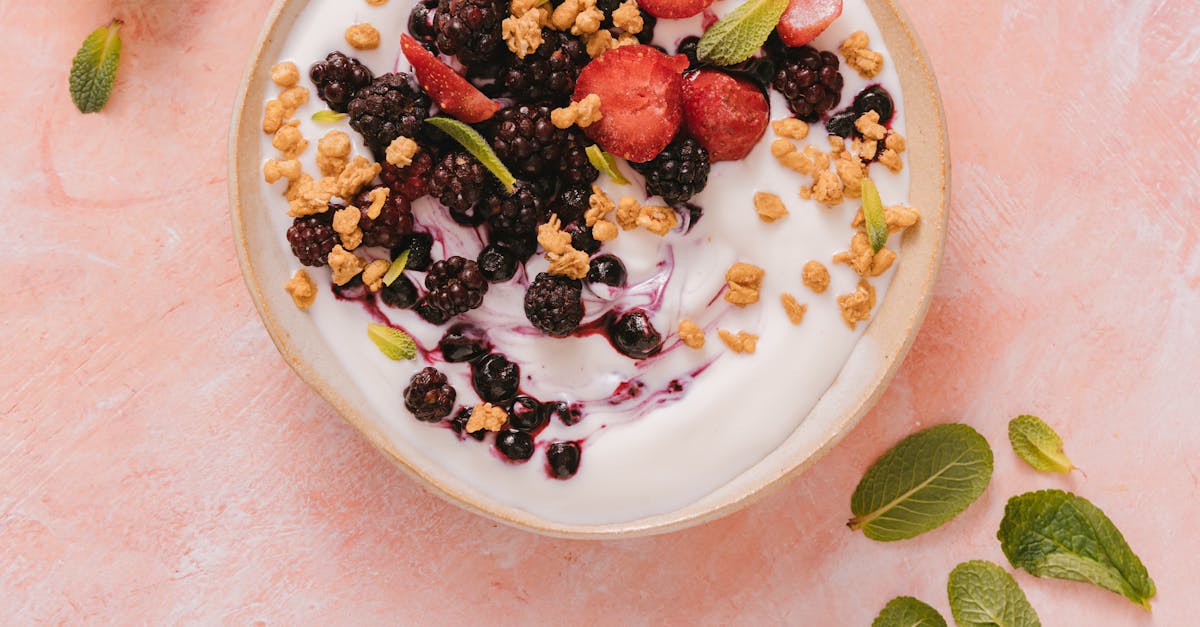 a fresh and delicious mixed berry yogurt bowl topped with granola and mint leaves