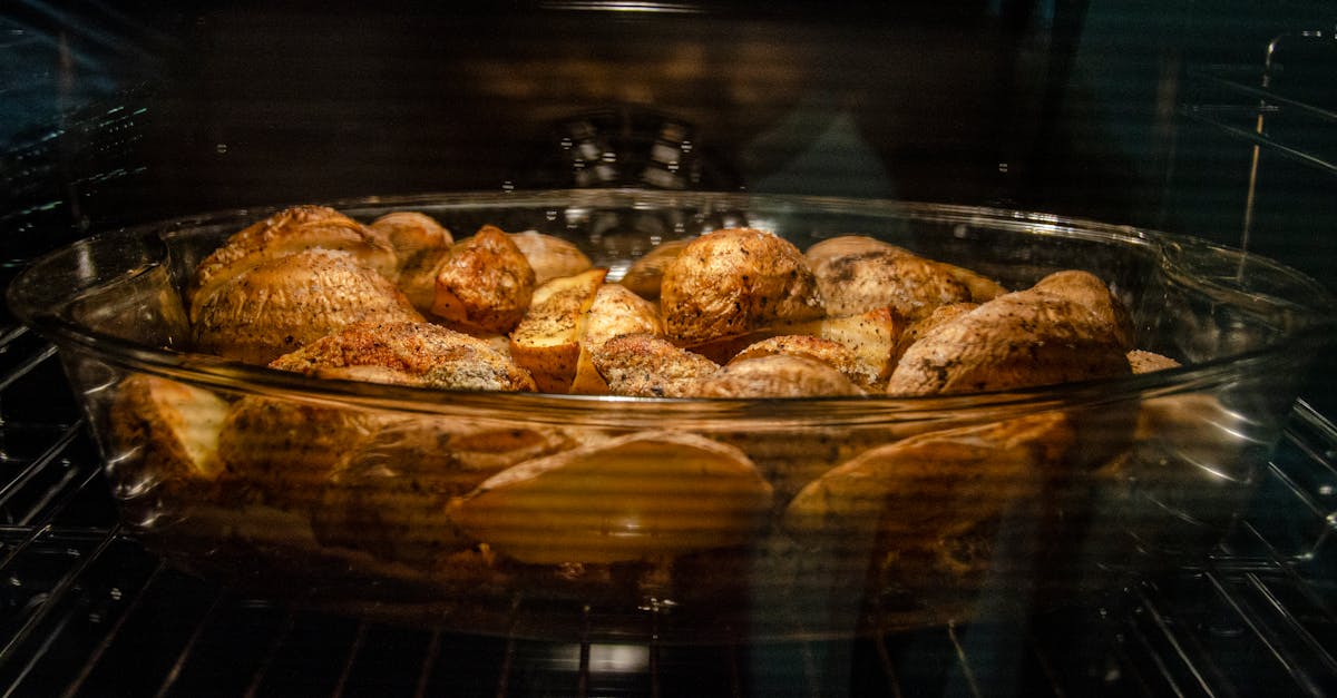 a glass dish filled with seasoned potatoes roasting in an oven creating a tasty homemade meal