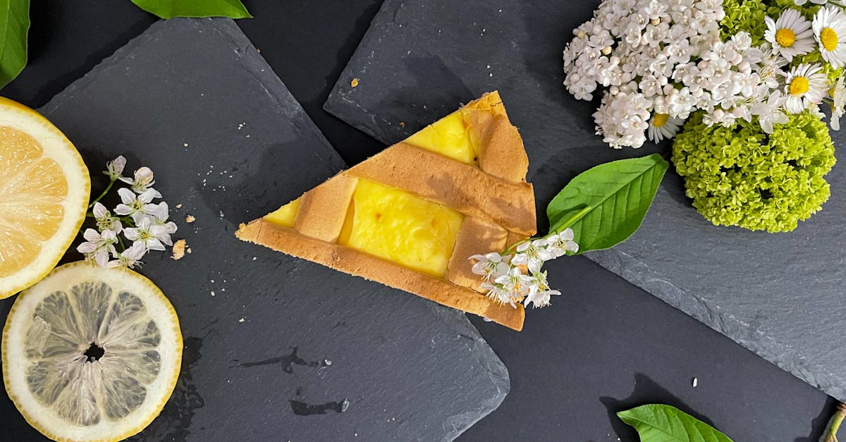 a lemon tart slice paired with spring flowers and lemons on slate perfect for food photography