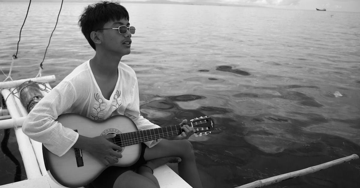 a man playing guitar on a boat in monochrome near lapu lapu city philippines