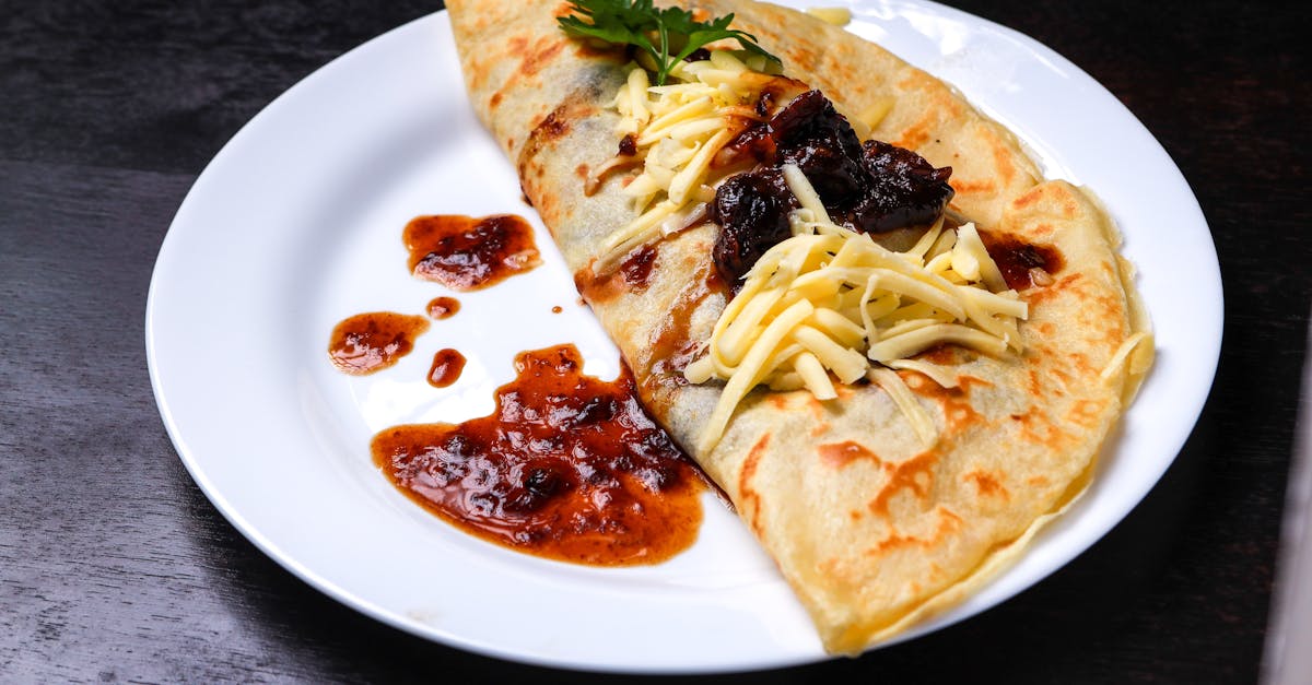 a mouthwatering crepe topped with melted cheese and fruit jam displayed on a white plate 3