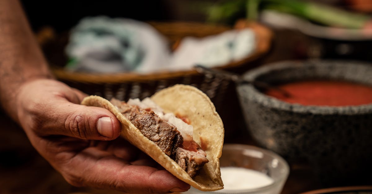 a person holding a delicious beef taco showcasing fresh ingredients in a vibrant kitchen setting