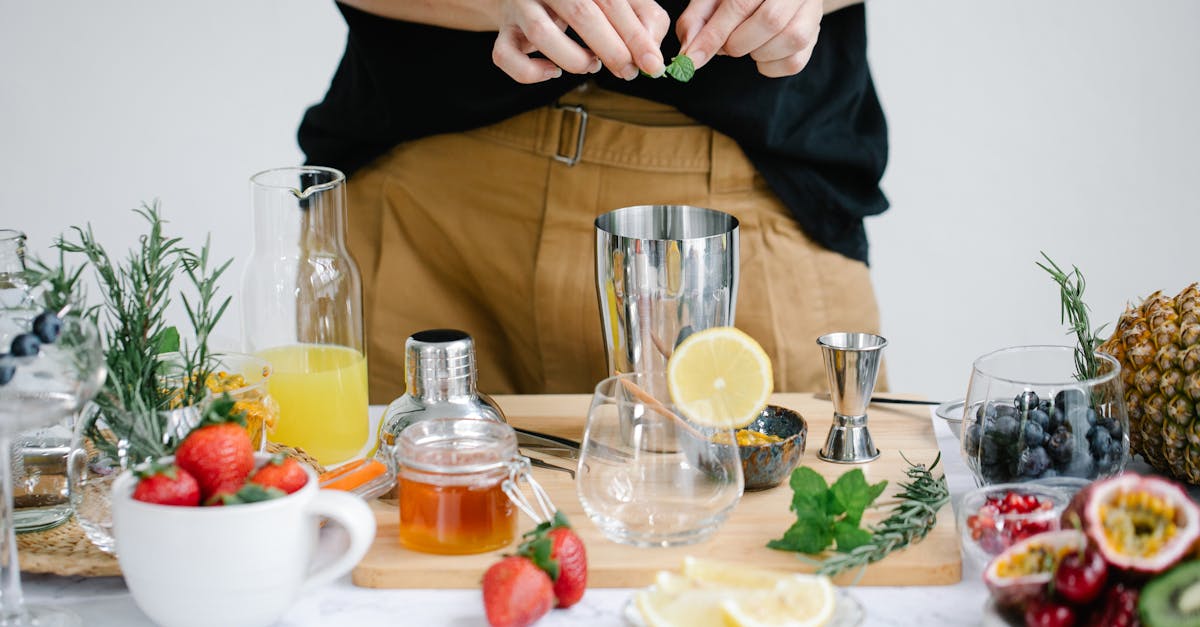 a person preparing a fresh cocktail with fruits herbs and honey indoors 1