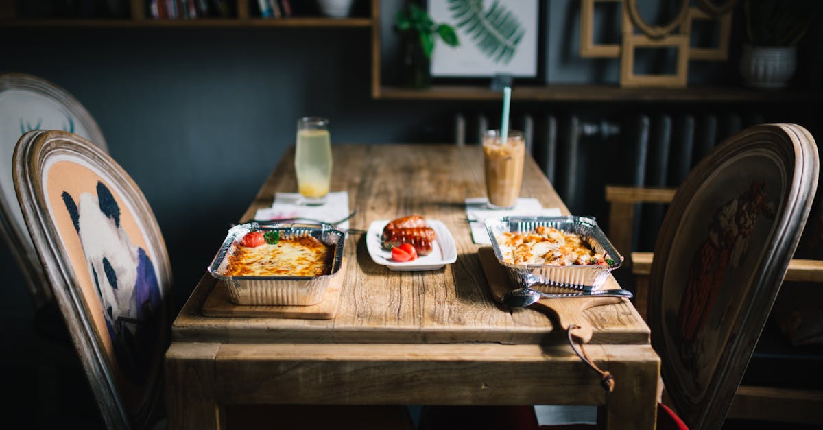 a rustic dining setup with served meals and beverages on a wooden table in a cozy indoor setting