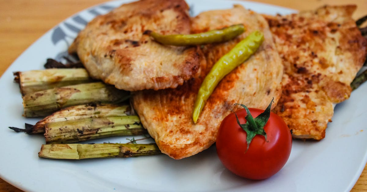 a savory plate of grilled chicken with asparagus and a fresh tomato 4