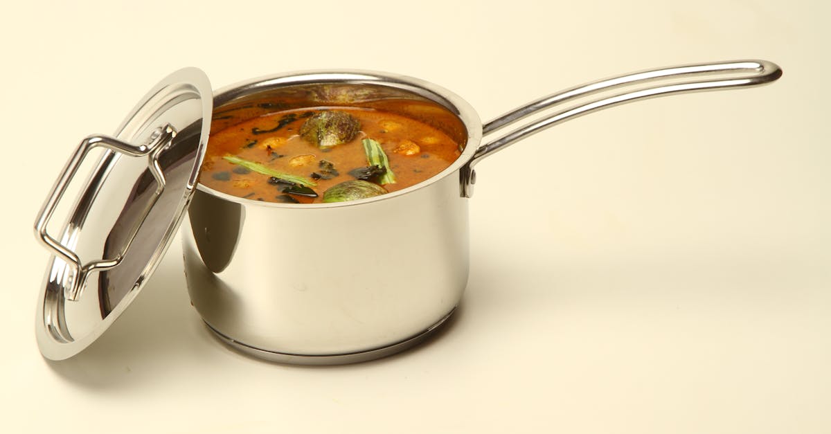 a stainless steel pot filled with traditional south indian sambar on a neutral background
