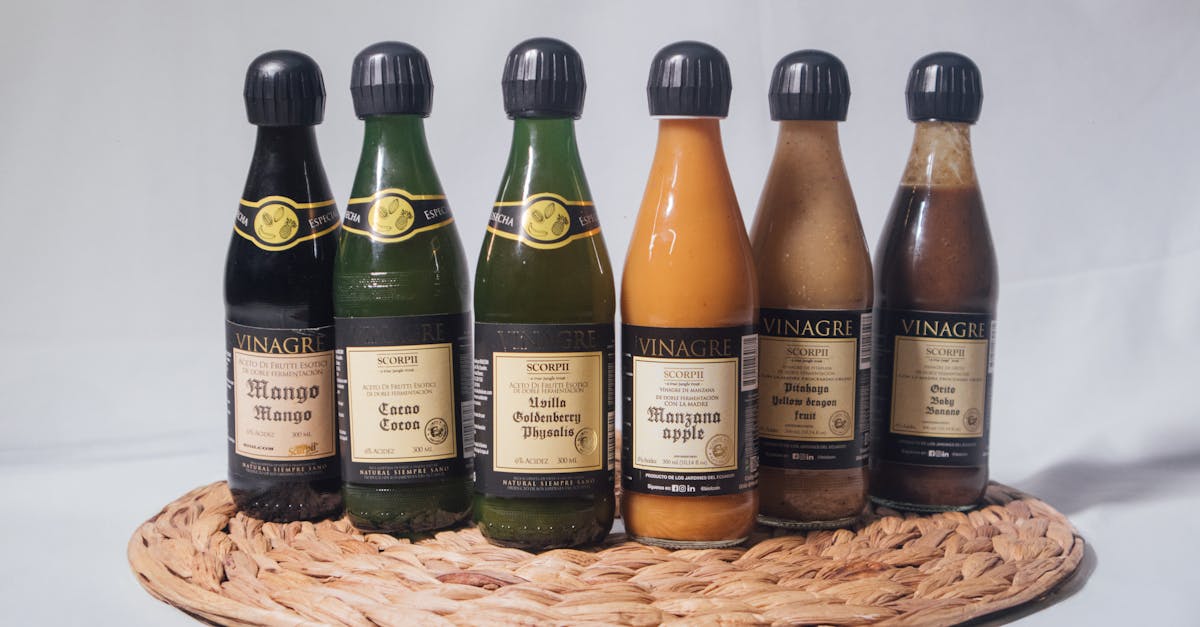 a variety of fruit flavored vinegar bottles displayed on a woven mat featuring mango apple and mo