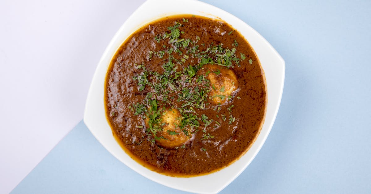 a vibrant and spicy indian egg curry garnished with fresh cilantro in a white bowl