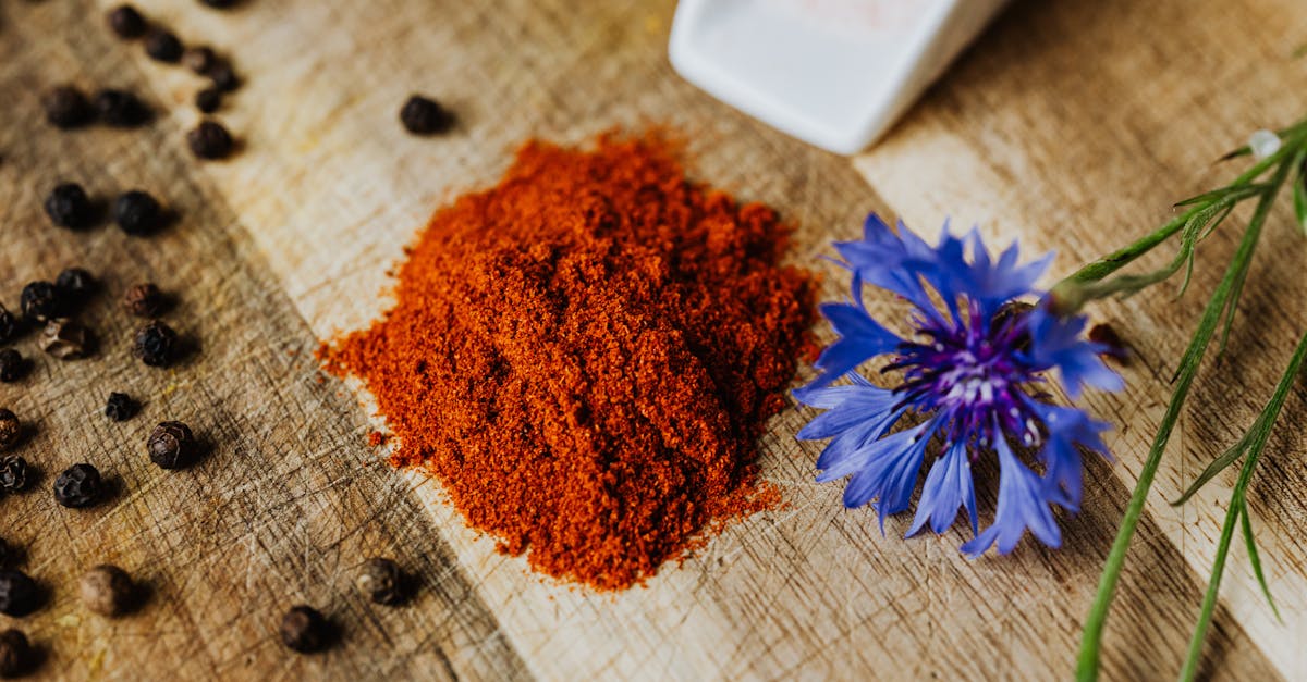 a vibrant display of paprika and peppercorns on a rustic wooden board with a cornflower accent perf