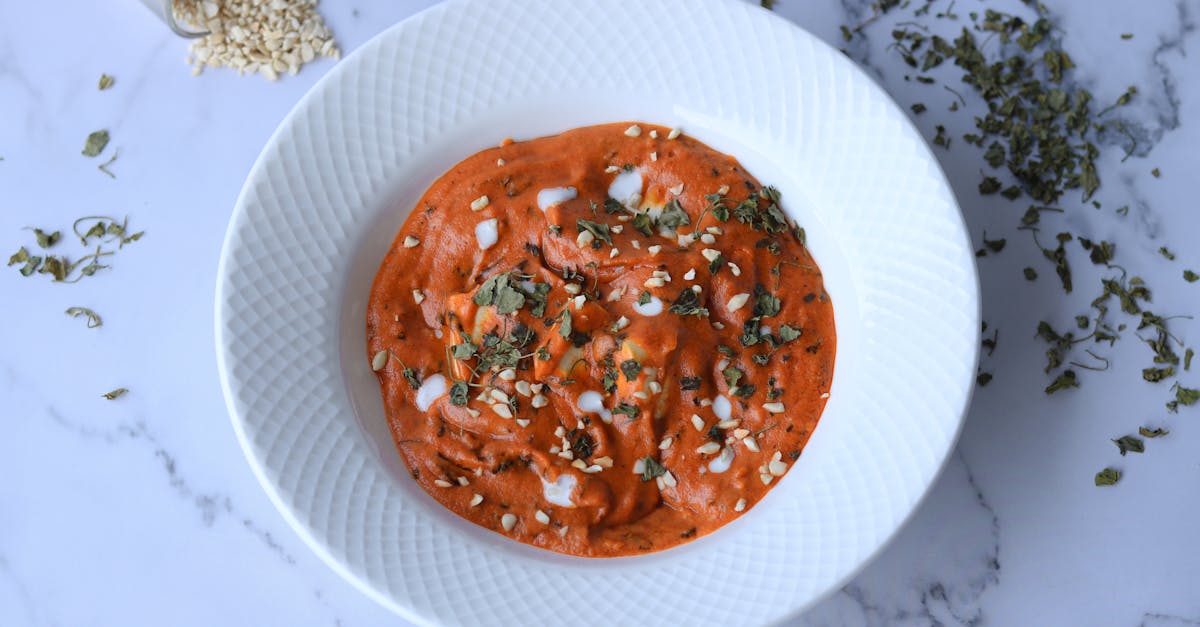 a vibrant muhammara dip garnished with herbs on a white plate perfect for healthy snacks