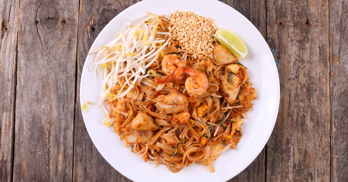 a vibrant plate of pad thai with shrimp peanuts and lime on a wooden table