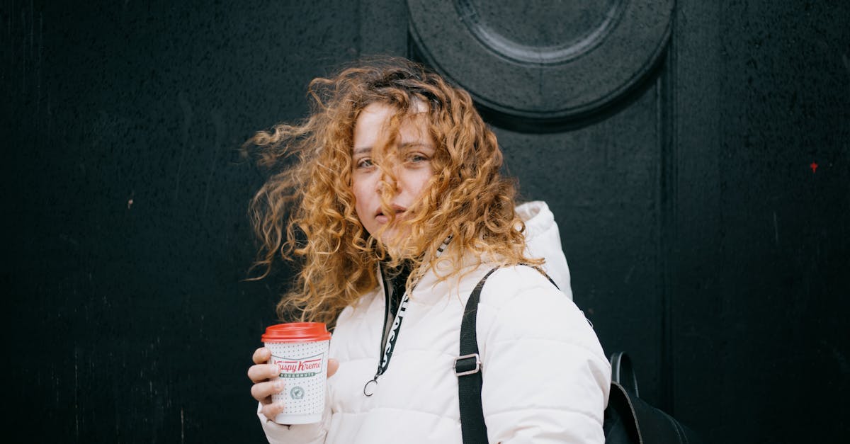 a woman with curly hair enjoying a warm coffee on a windy day in glasgow 1