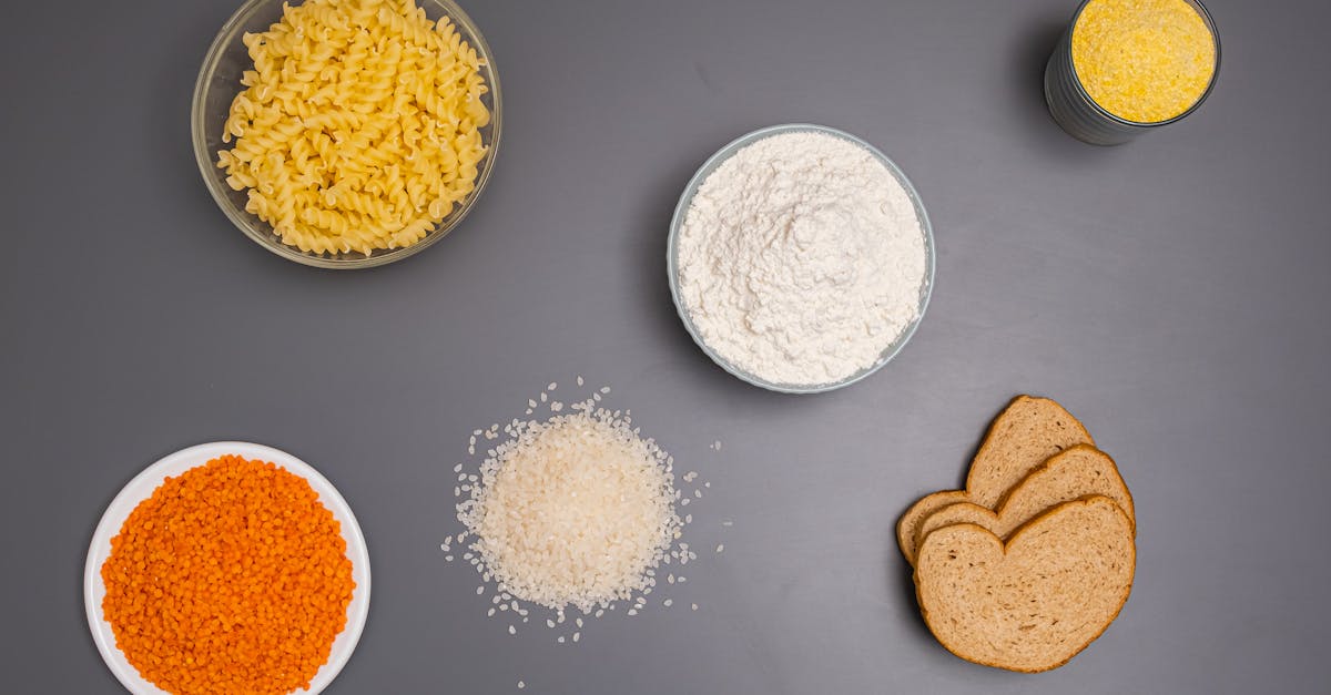 an assortment of dry ingredients including pasta rice and bread displayed on a grey background