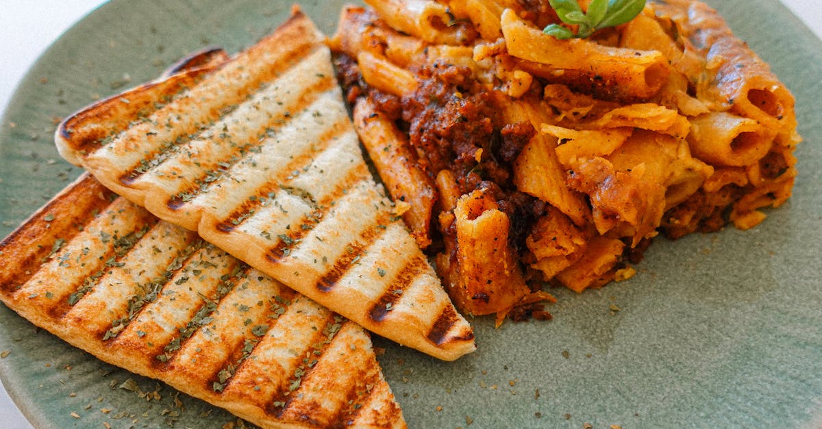 appetizing cheesy penne paired with grilled bread on a rustic green plate perfect for italian cuisi