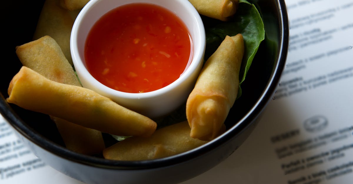 appetizing close up of crispy spring rolls served with a tangy red dipping sauce