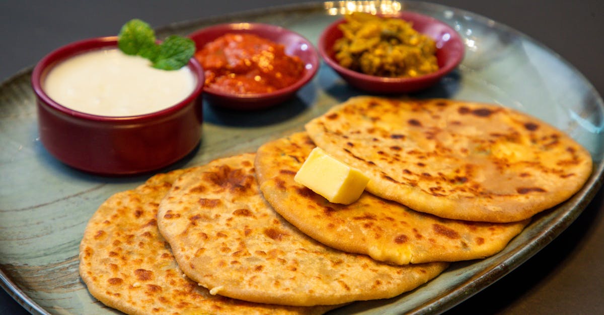 appetizing indian paratha served with yogurt and pickles on a blue plate