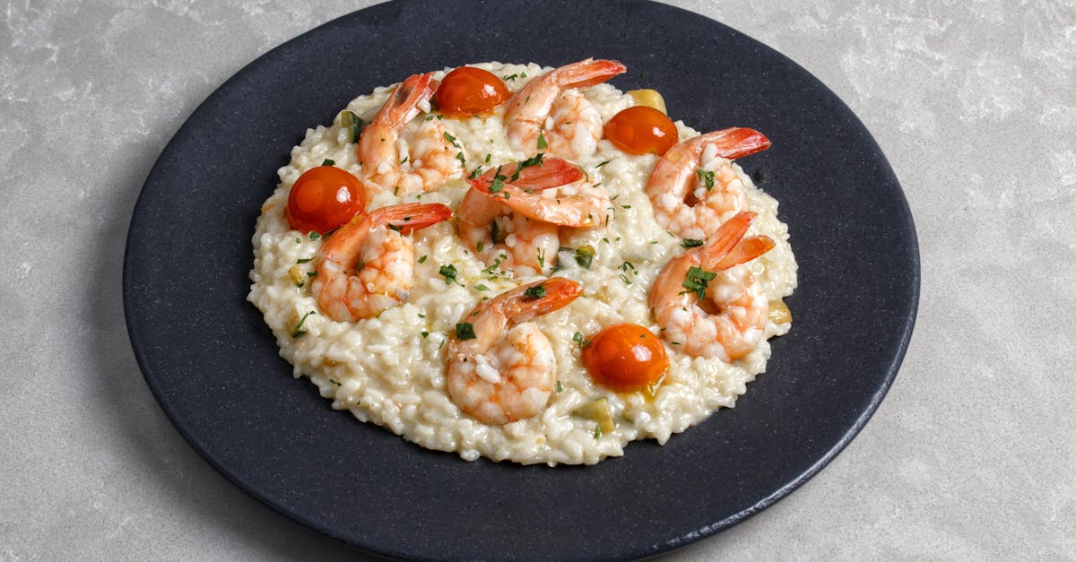 appetizing shrimp risotto topped with cherry tomatoes on a black plate