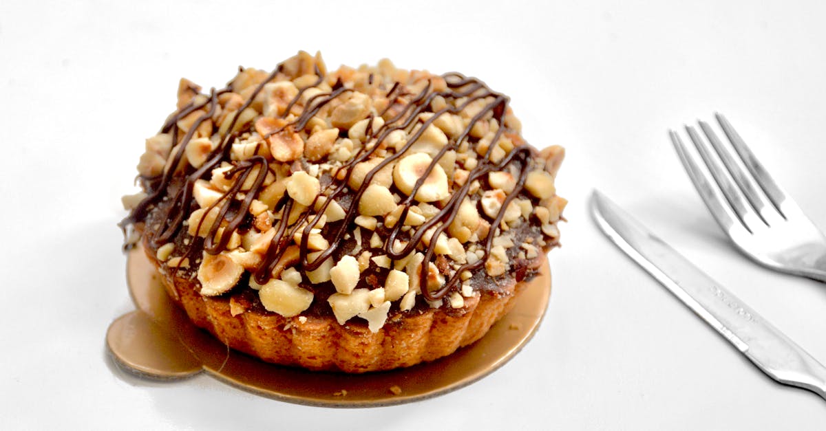appetizing sweet pie tart with shortcrust pastry and chopped nuts topped with chocolate sauce on whi