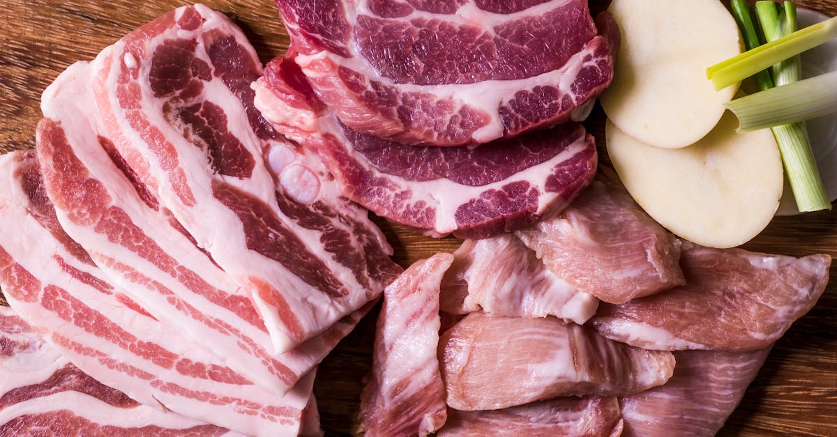 assorted raw meat cuts displayed on a wooden chopping board with sliced potatoes and spring onions 2