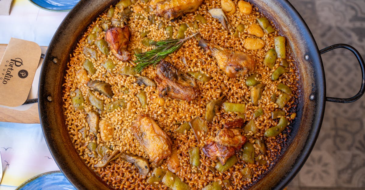 authentic valencia paella in a pan with chicken vegetables and rosemary top view