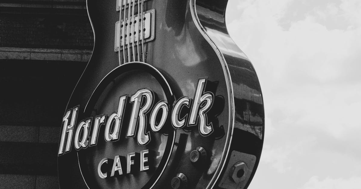 Home black and white photo of the hard rock cafe guitar shaped sign against a cloudy sky
