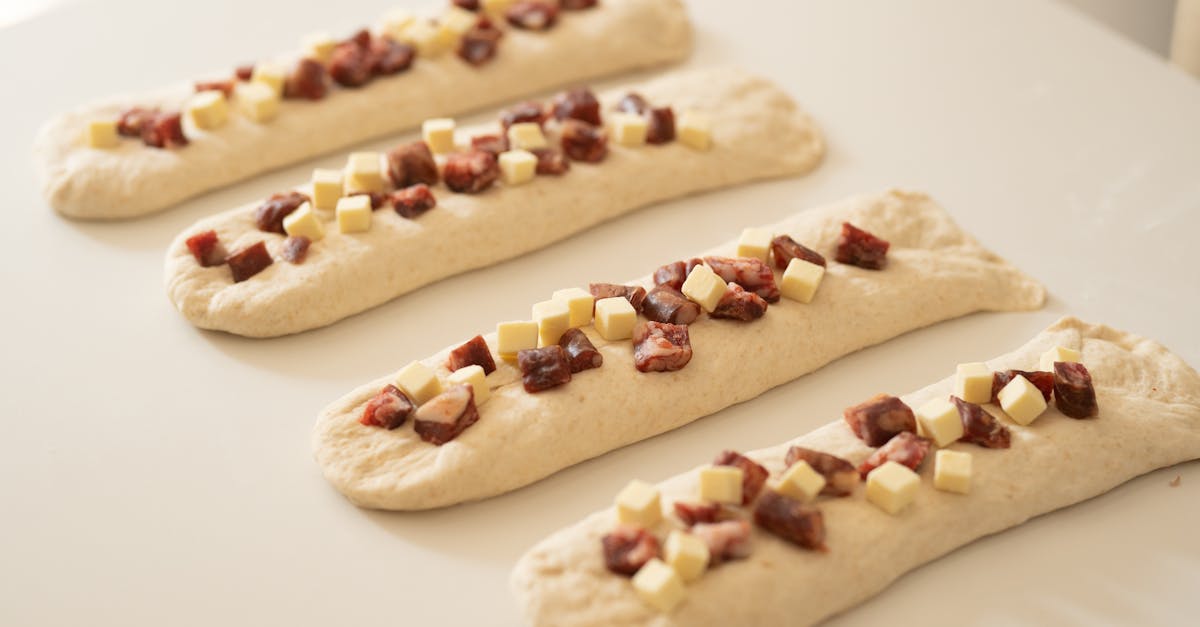 bread dough topped with cubes of cured meat and cheese ready for baking