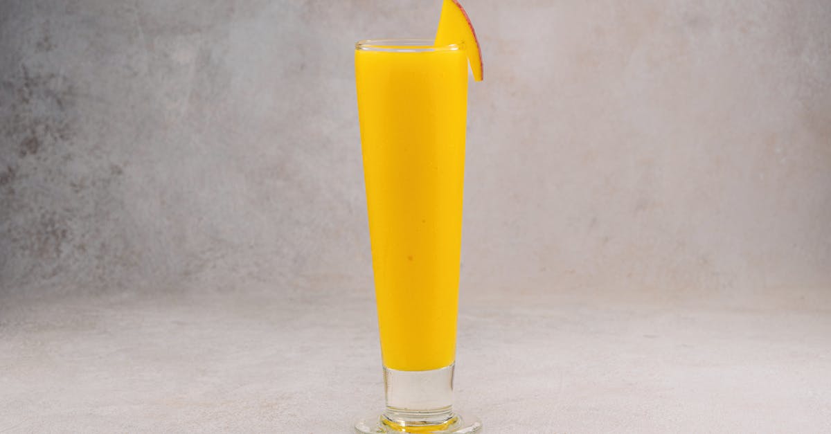 bright mango smoothie in a tall glass with a mango slice perfect for food photography
