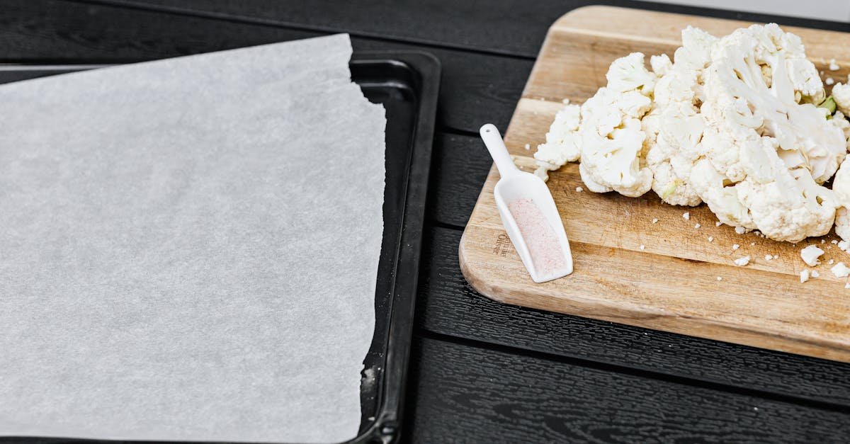 cauliflower on a cutting board next to a lined baking tray ready for cooking